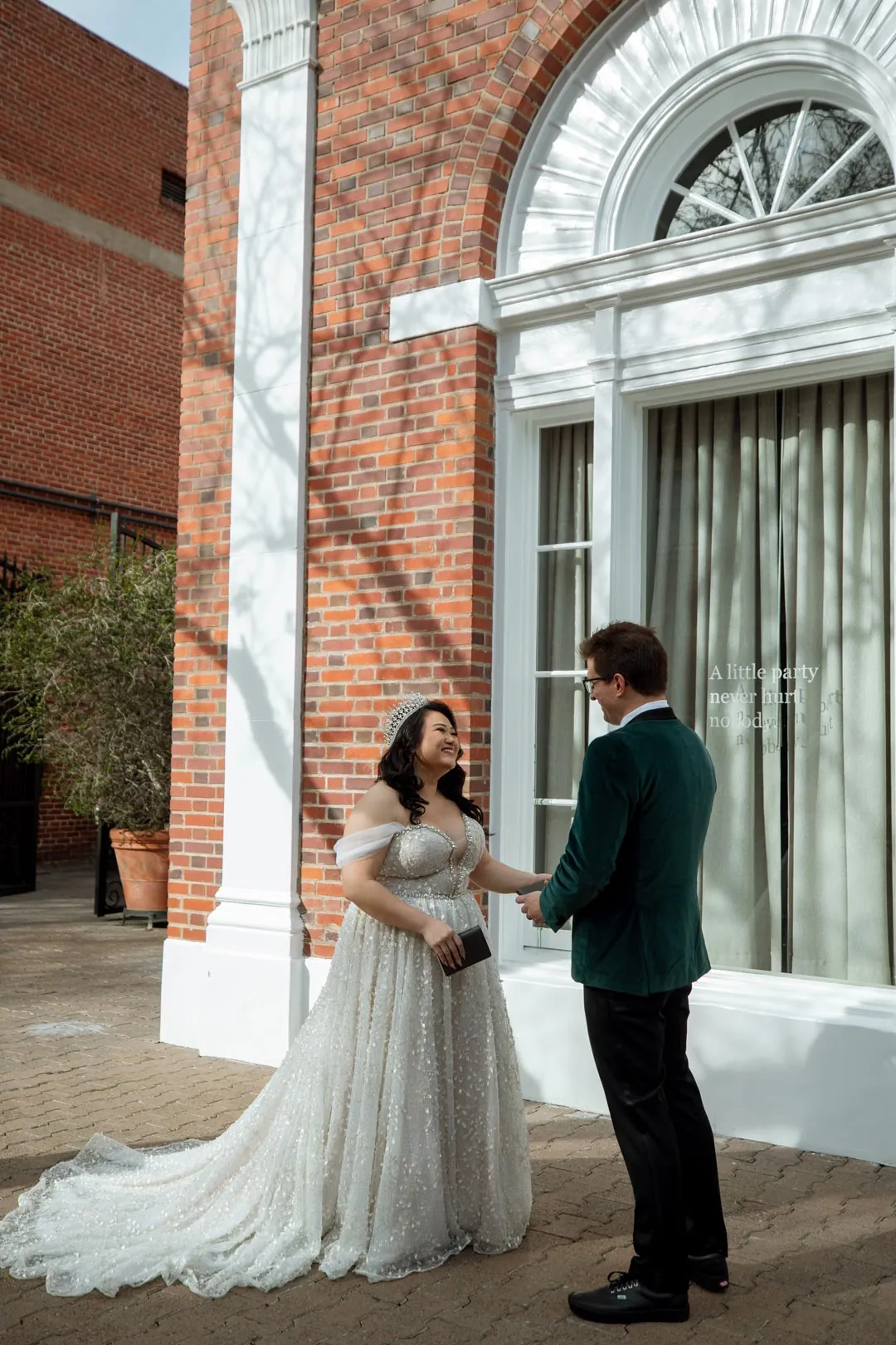 Couple holding hands before a tall arched window