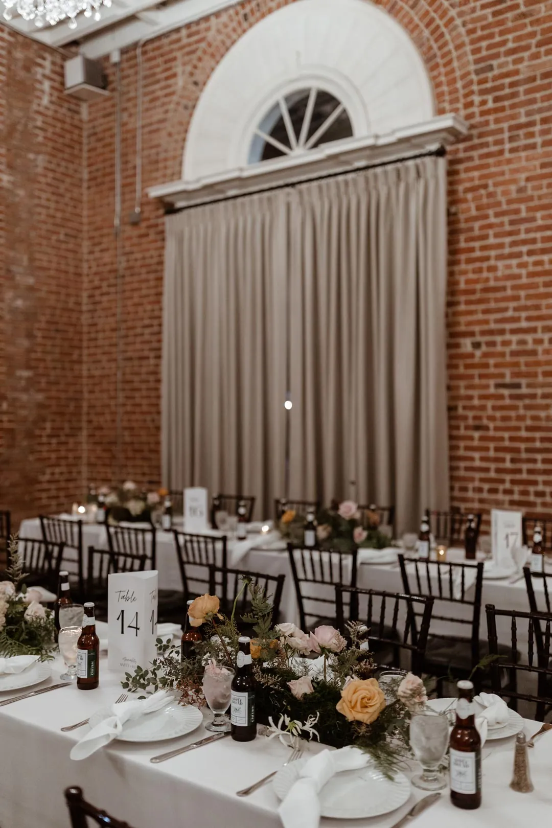 Reception tables set beside a large draped arched window