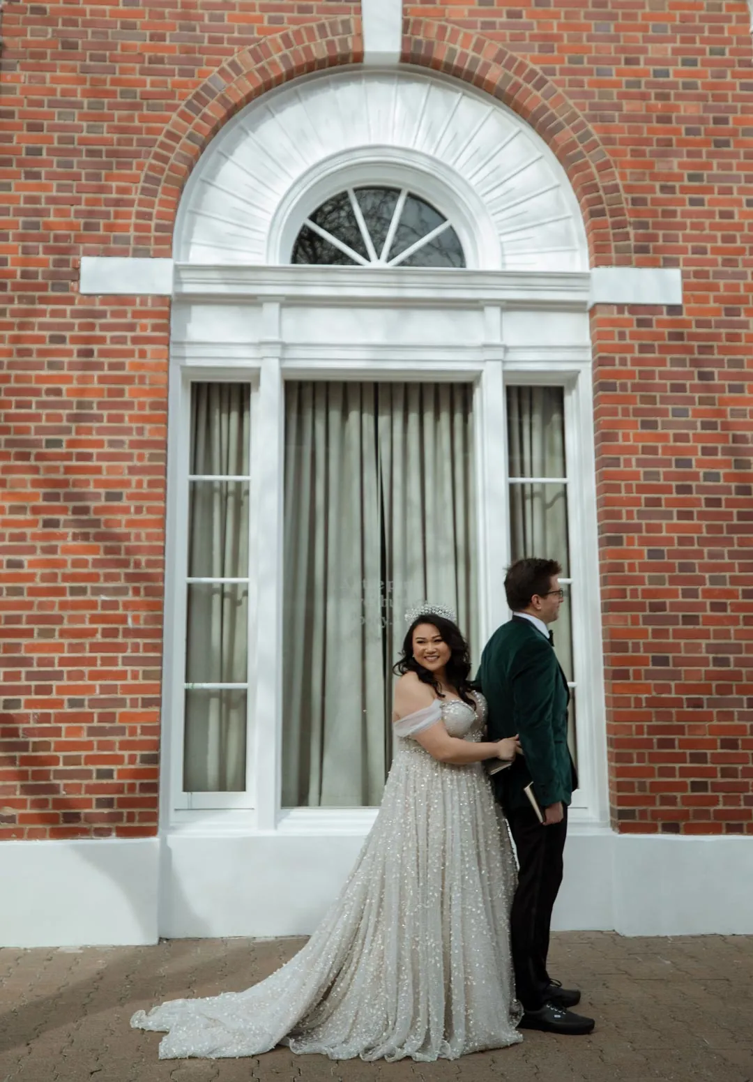 Couple leaning together beside a tall arched window