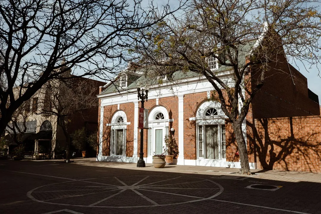 Brick corner building with arched windows beneath bare tree branches