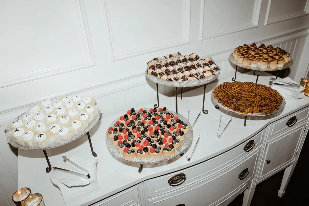 Assorted desserts arranged on stands on a white dresser