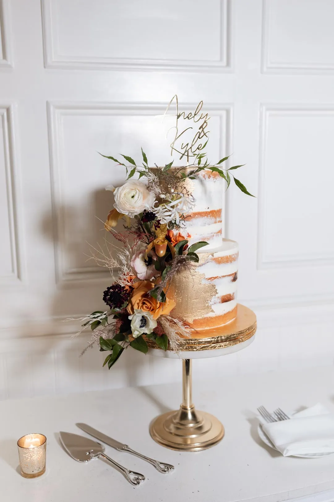 Tiered wedding cake with exposed sponge layers and flowers