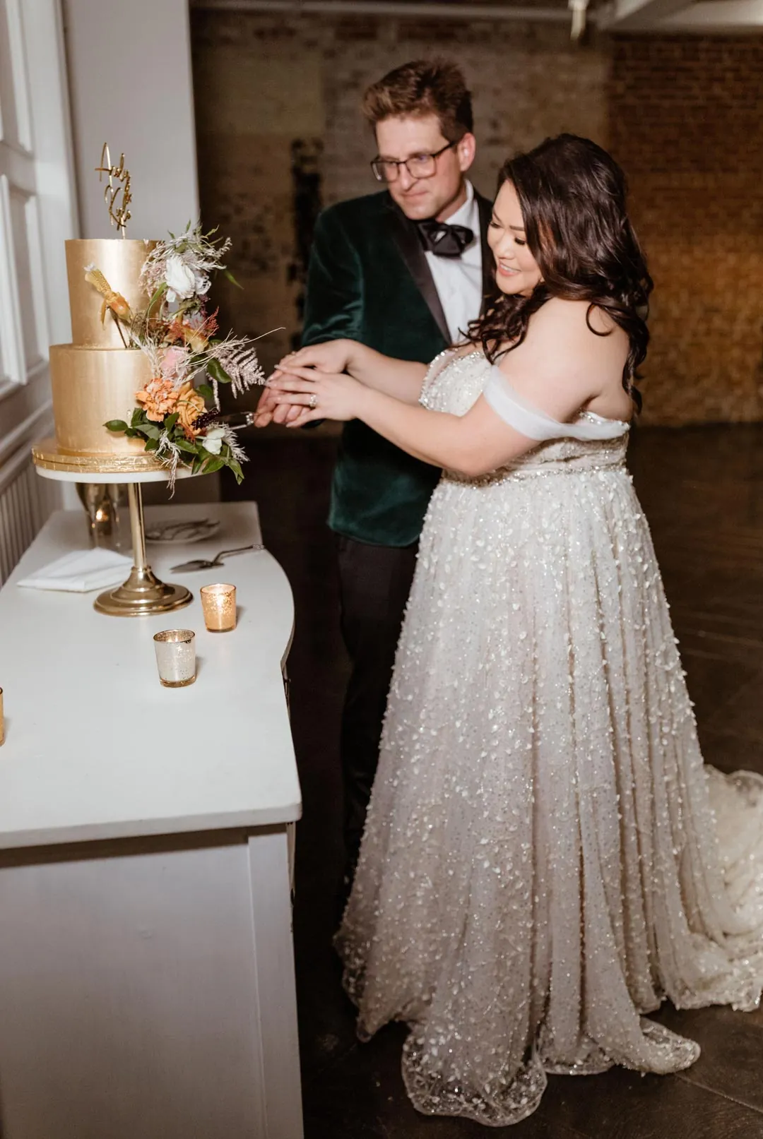 Couple cutting a wedding cake displayed on a dresser