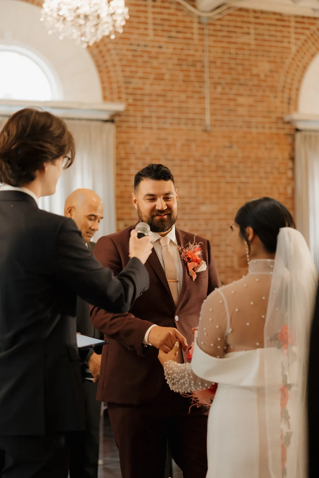 Groom faces the bride while holding her hands.