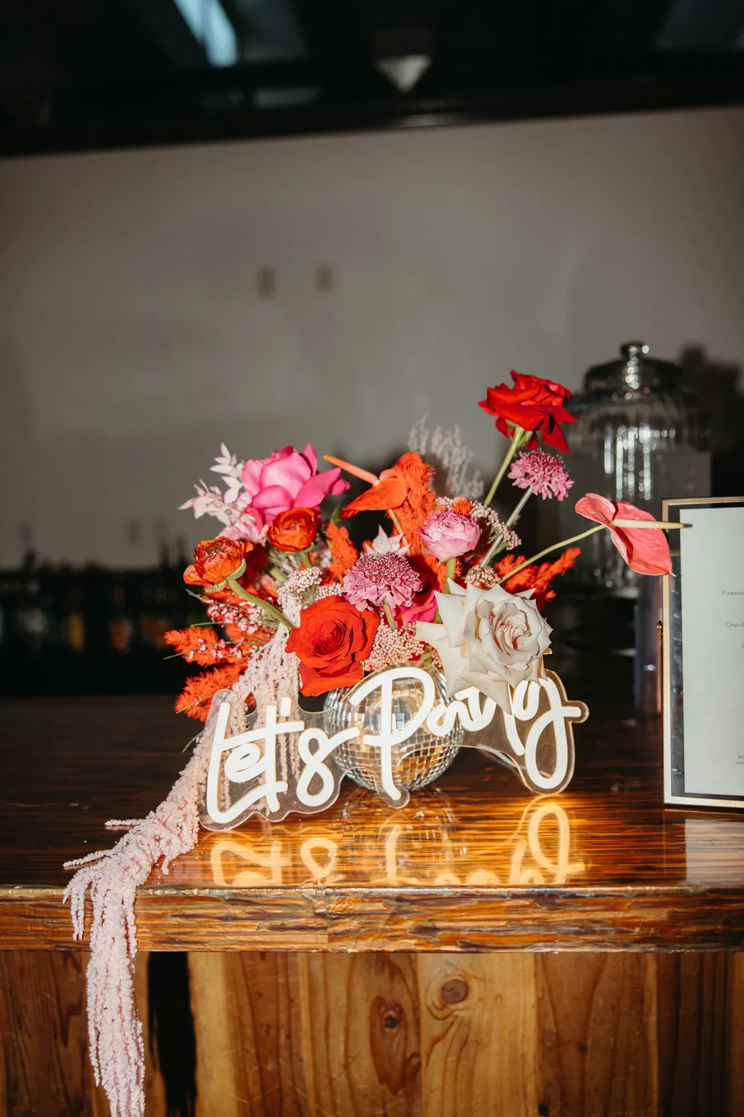 Red floral arrangement beside a glowing bar sign.