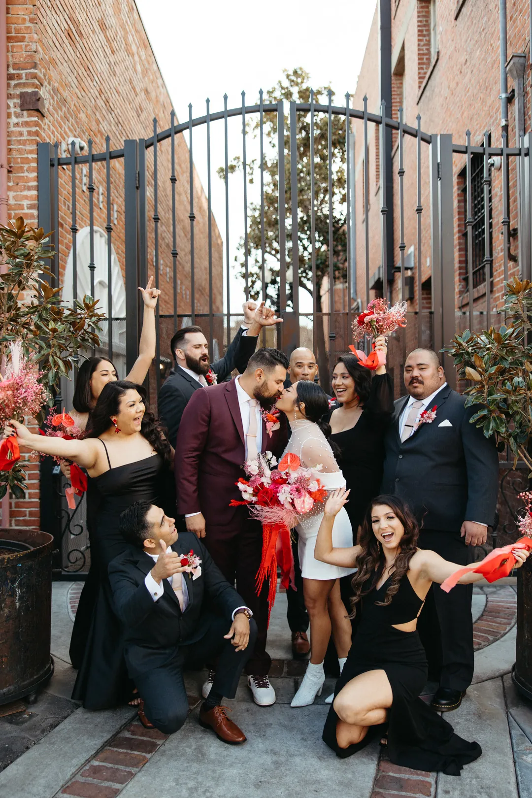 Wedding party pose at an open iron courtyard gate.