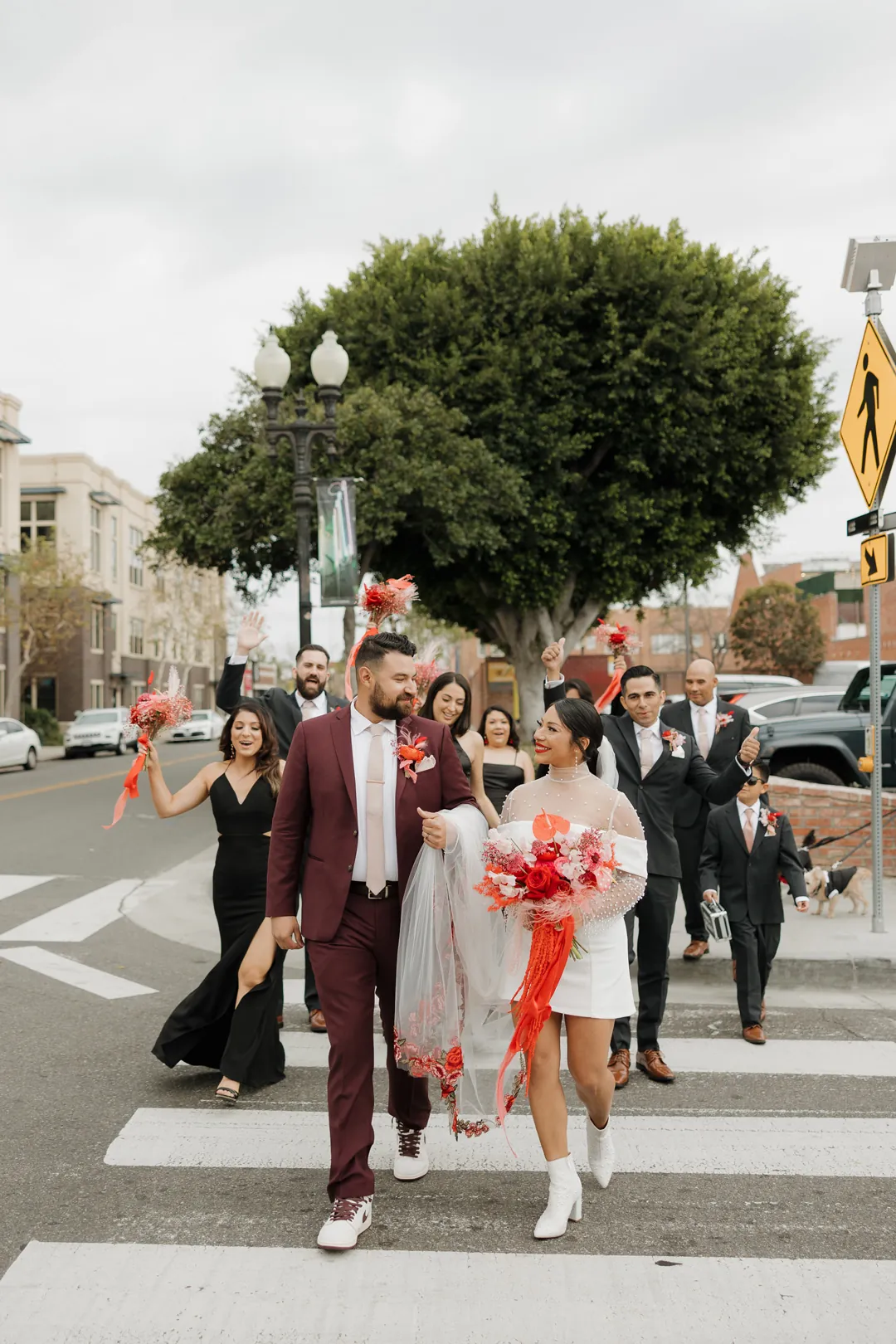Couple cross a city street with their wedding party.