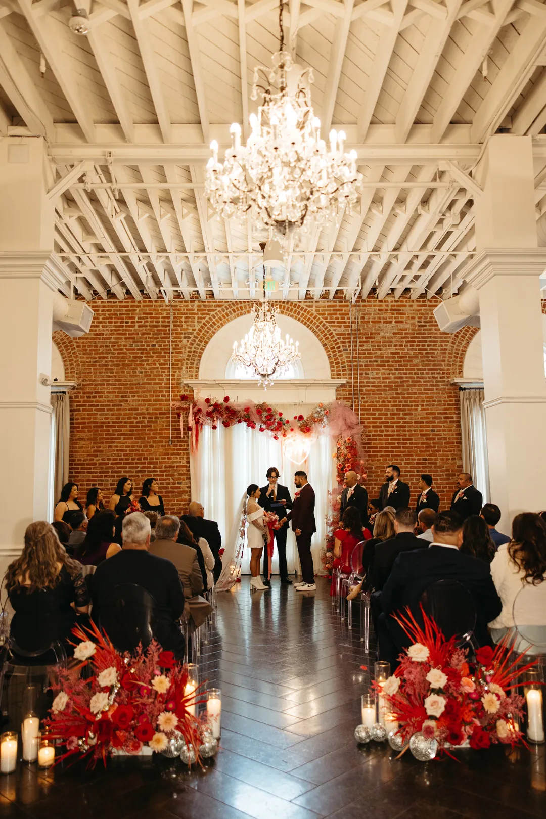 Guests face the couple during a ballroom ceremony.