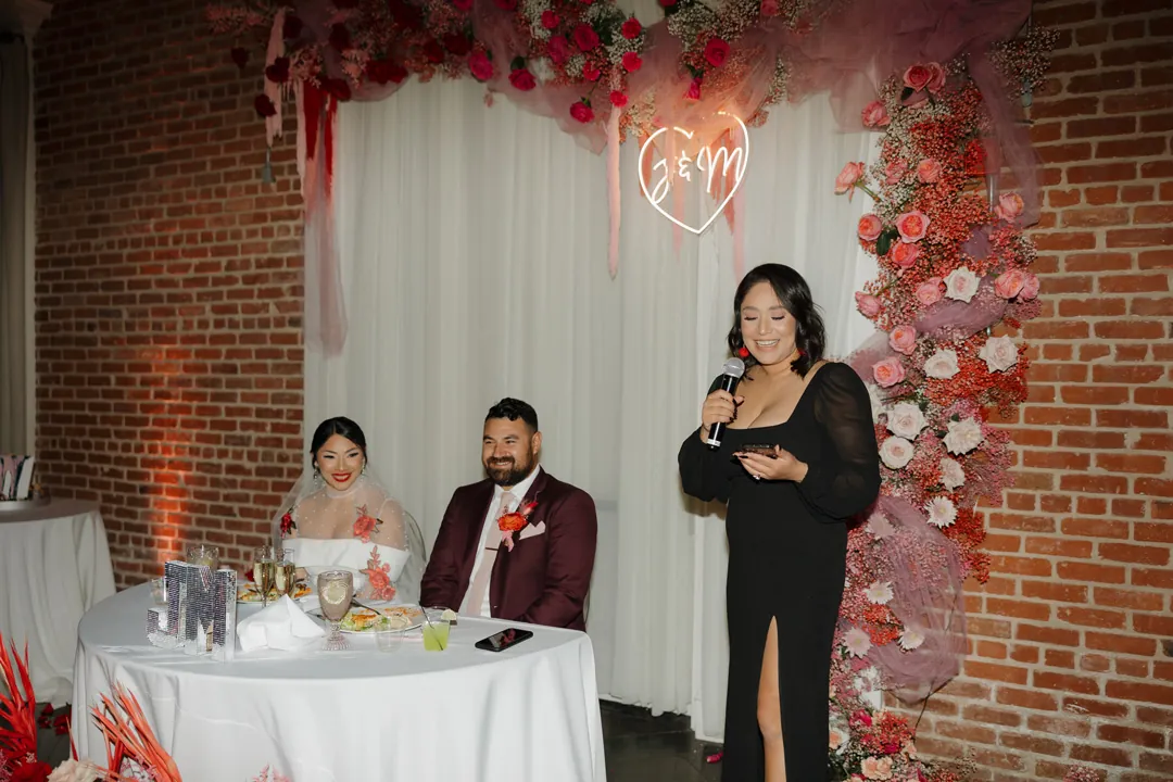 Guest gives a toast beside the seated newlyweds.