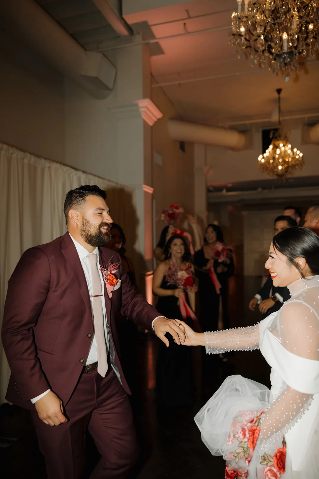 Couple reach toward each other on the reception floor.
