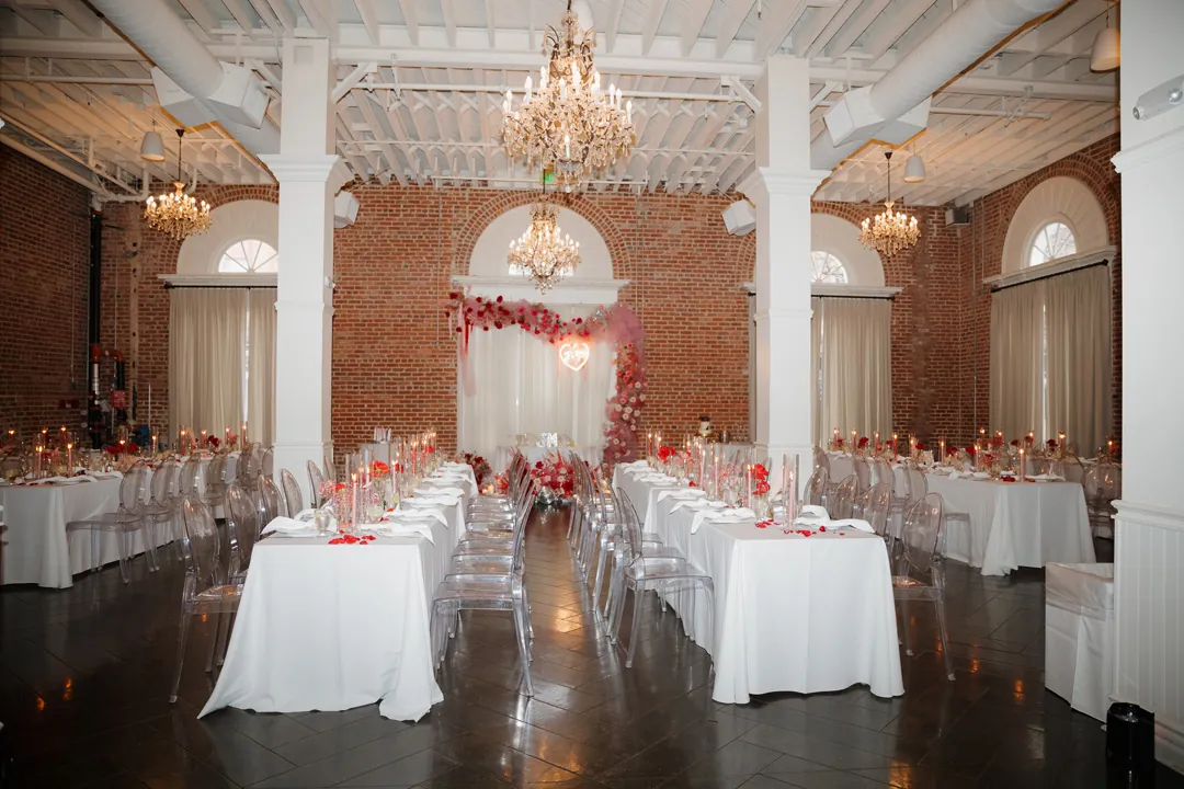 Round reception tables beneath white ceiling beams.