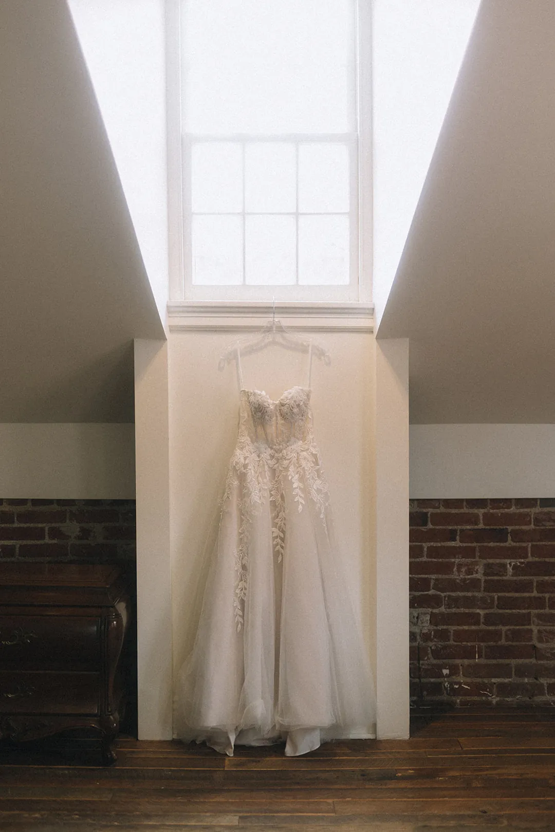Wedding dress hanging beneath a stairwell window