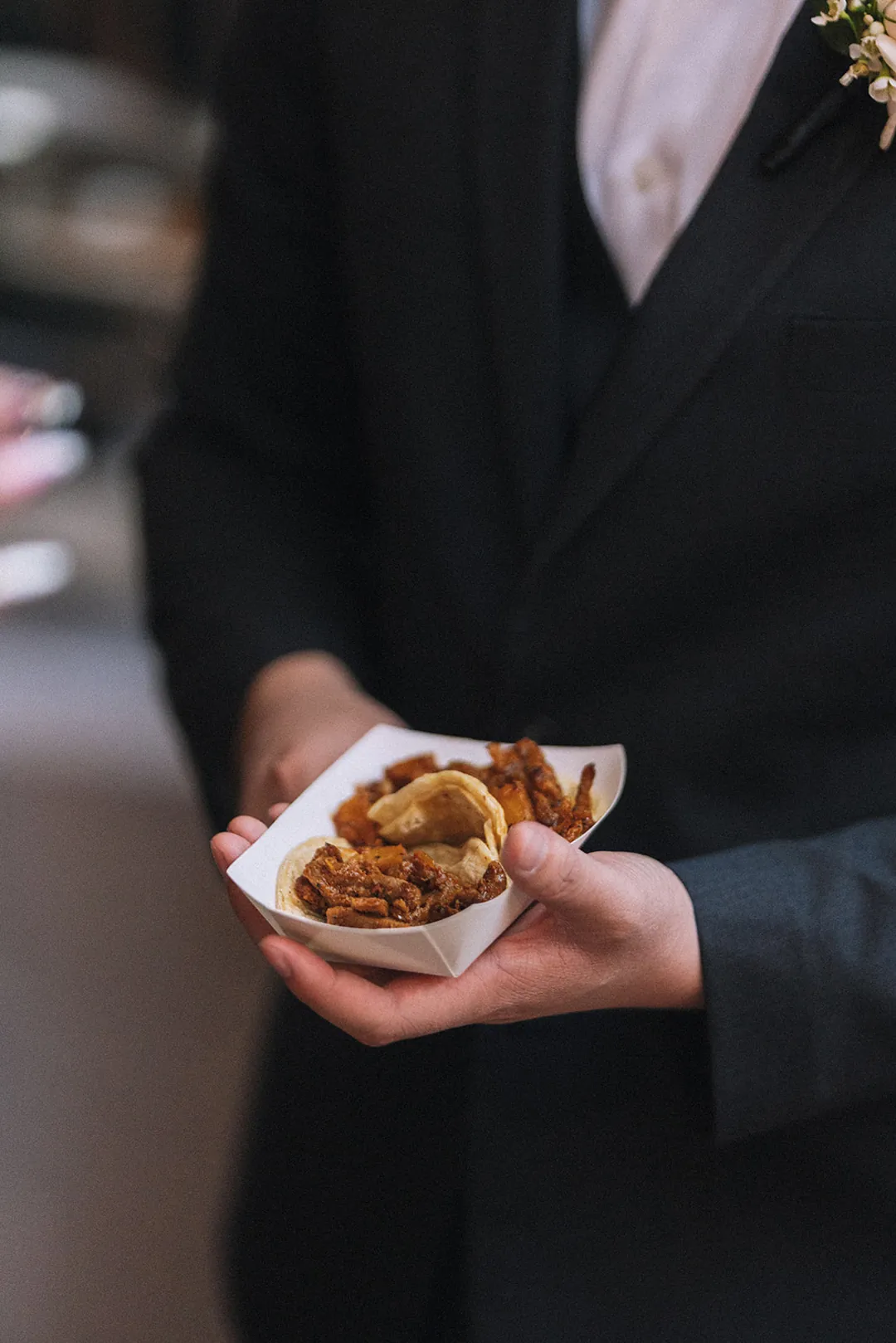 Guest holding a small appetizer in a paper tray