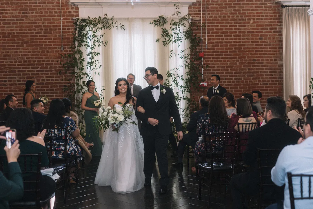 Newlyweds celebrating as they walk down the aisle