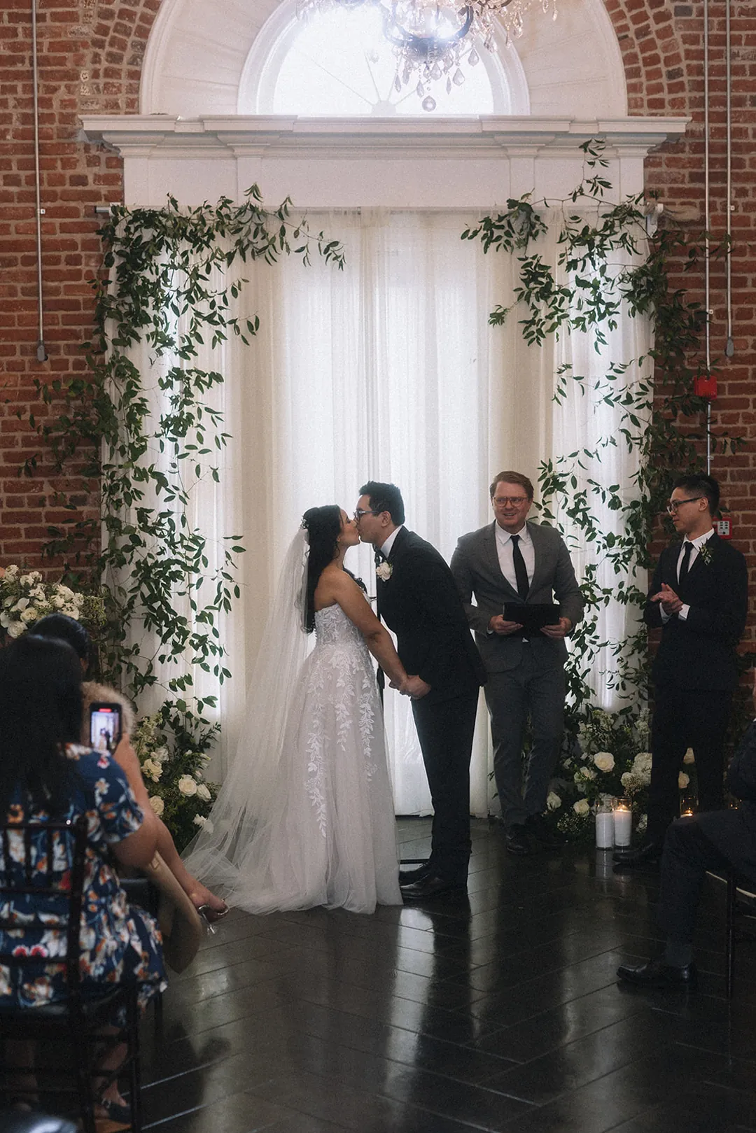 Bride and groom standing beneath a floral arch