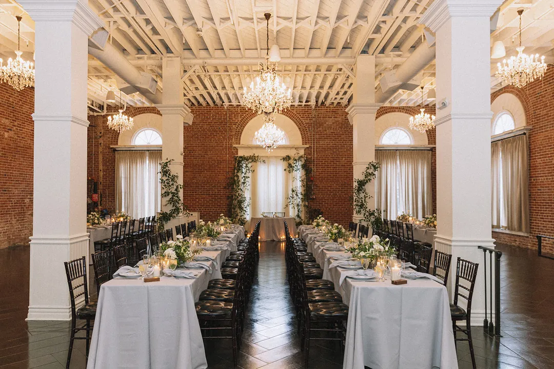 Parallel reception tables beneath ballroom chandeliers
