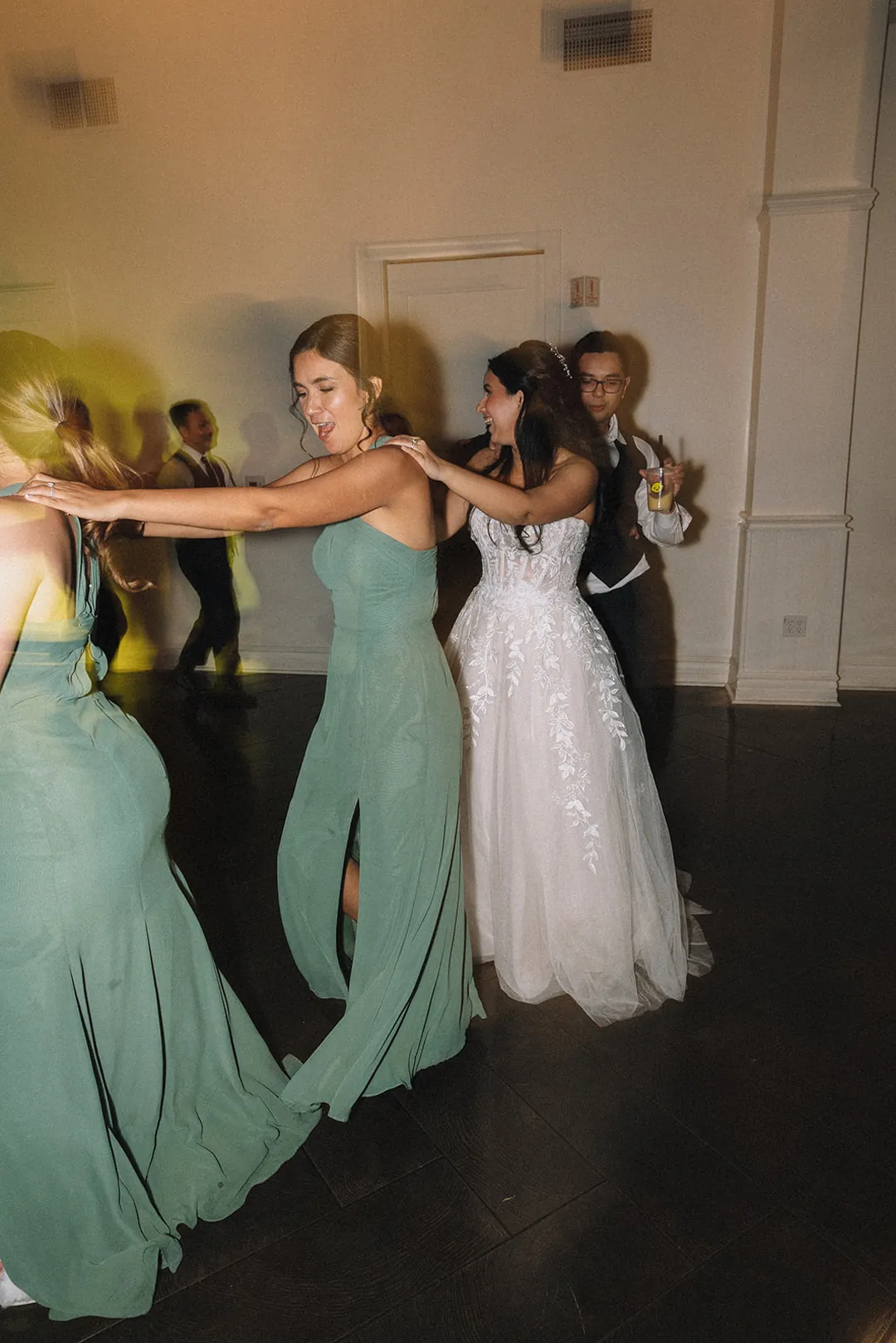 Bride dancing with attendants in green dresses