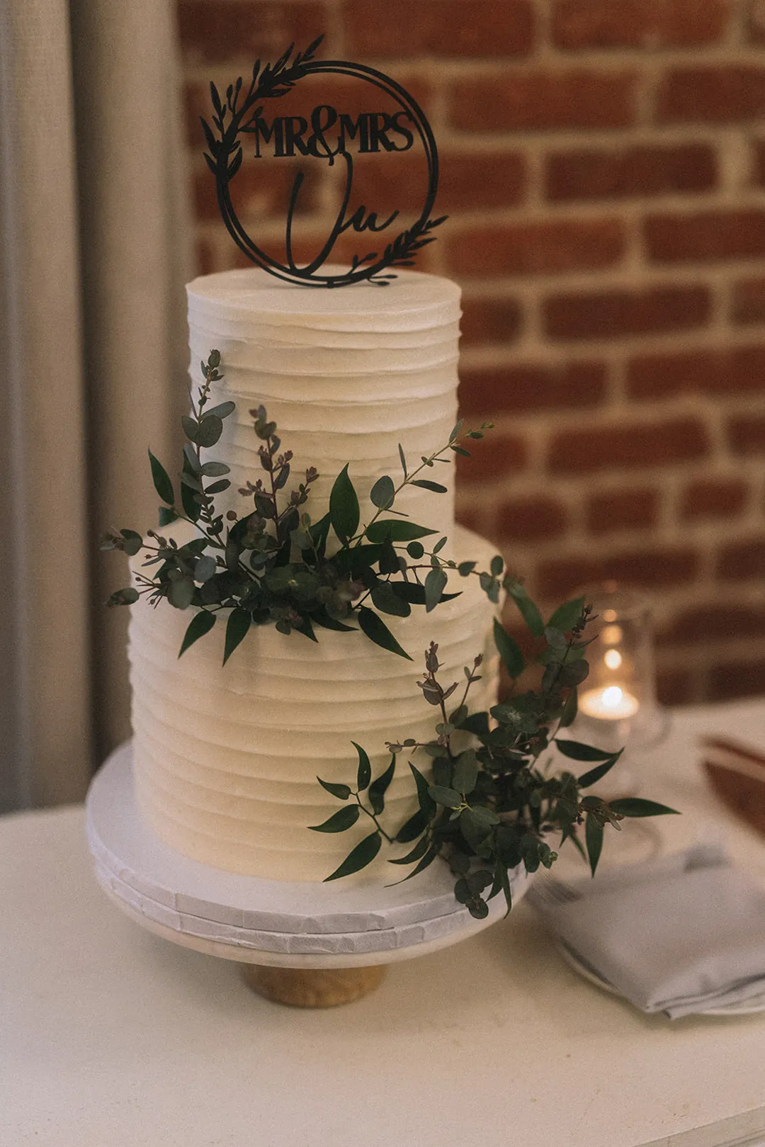 White tiered wedding cake decorated with greenery