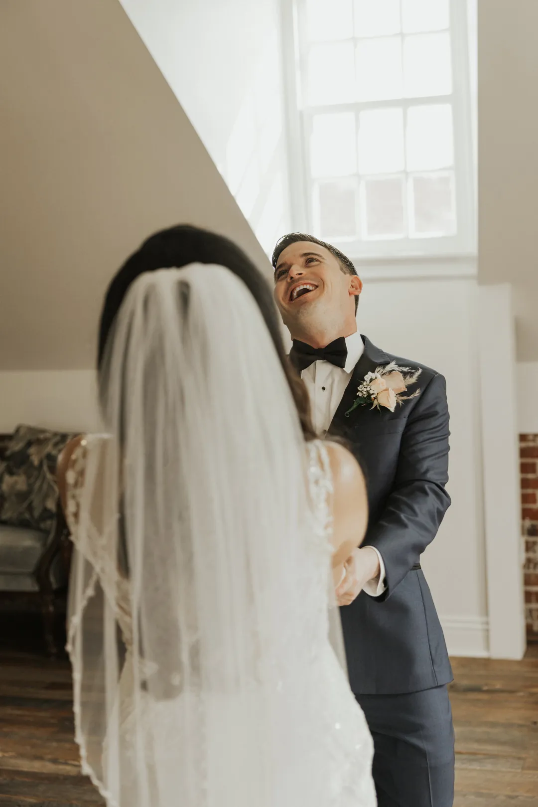 Groom reacts while facing a veiled bride.