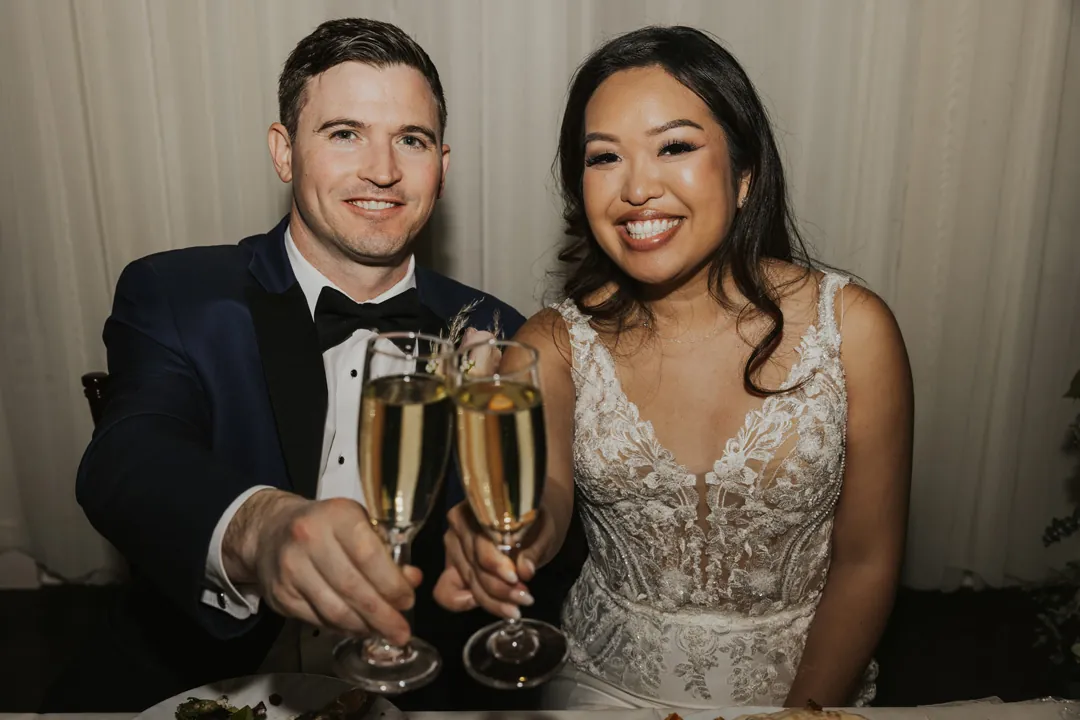 Newlyweds hold champagne flutes for a portrait.