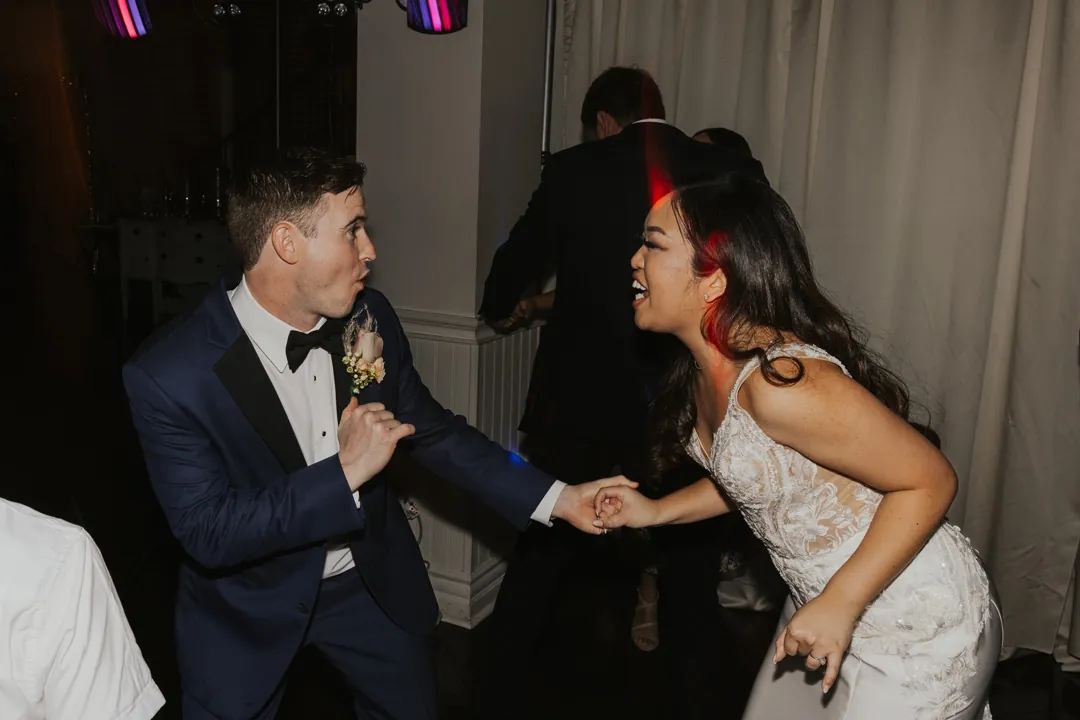 Couple laugh while dancing during their reception.