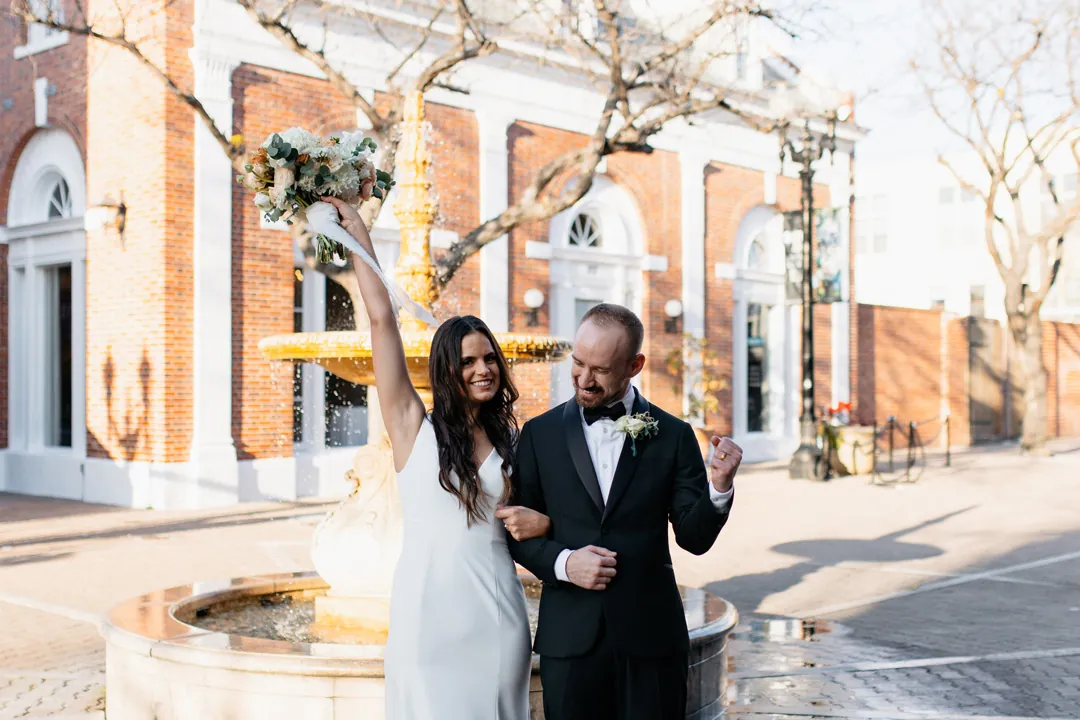 Newlyweds holding hands outside a brick building