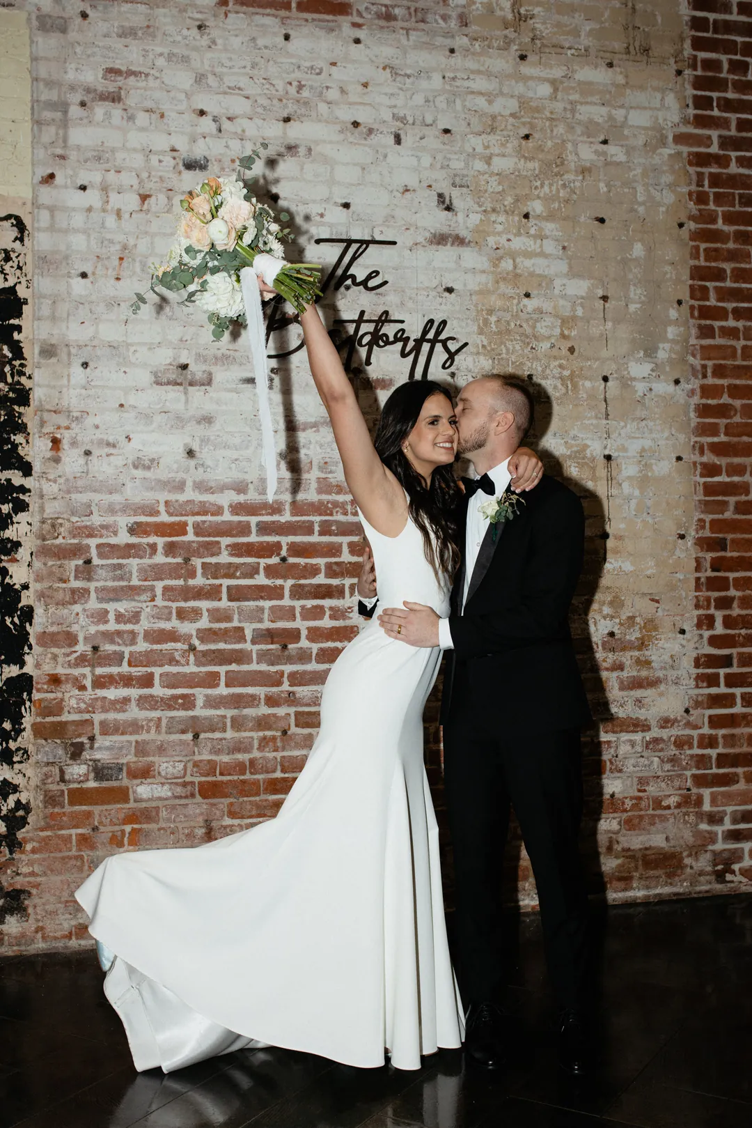 Bride holding a bouquet aloft beside the groom