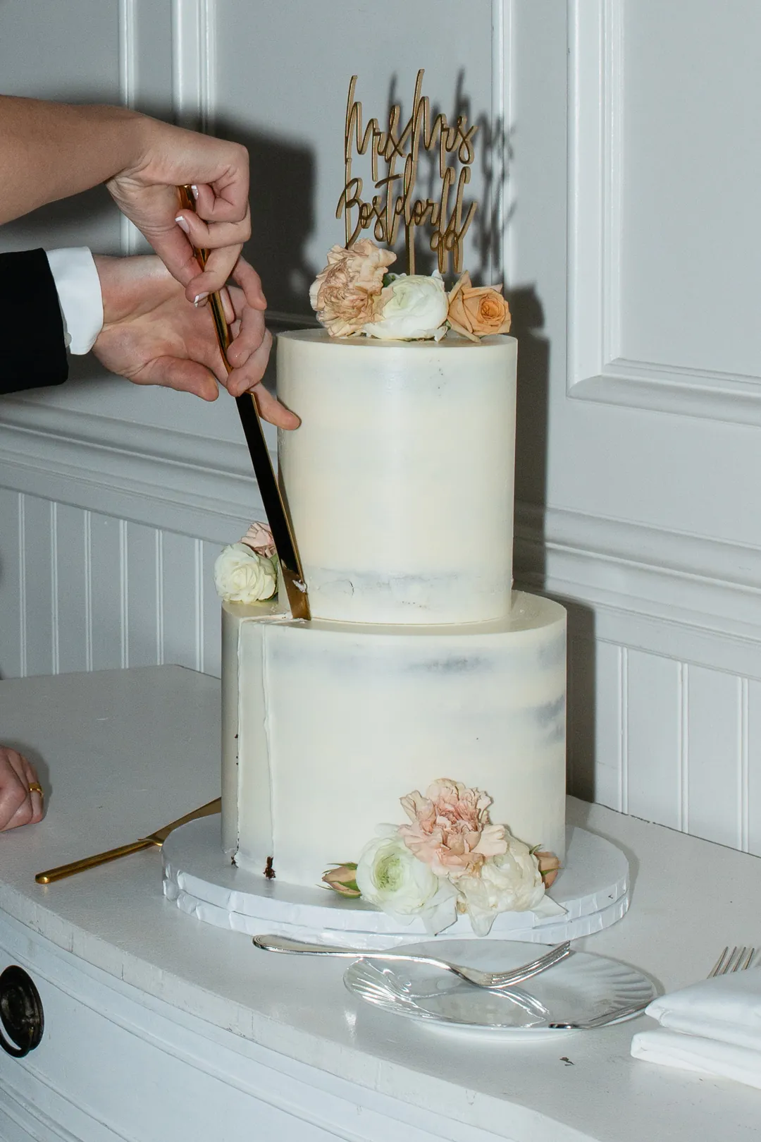 Couple cutting a white tiered wedding cake