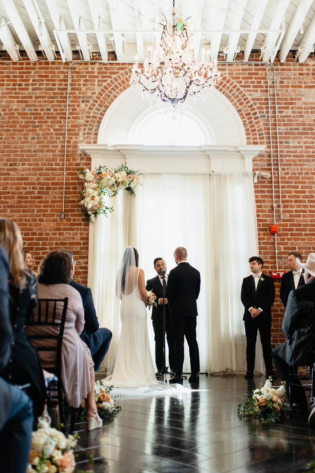Couple exchanging vows beneath an arched window