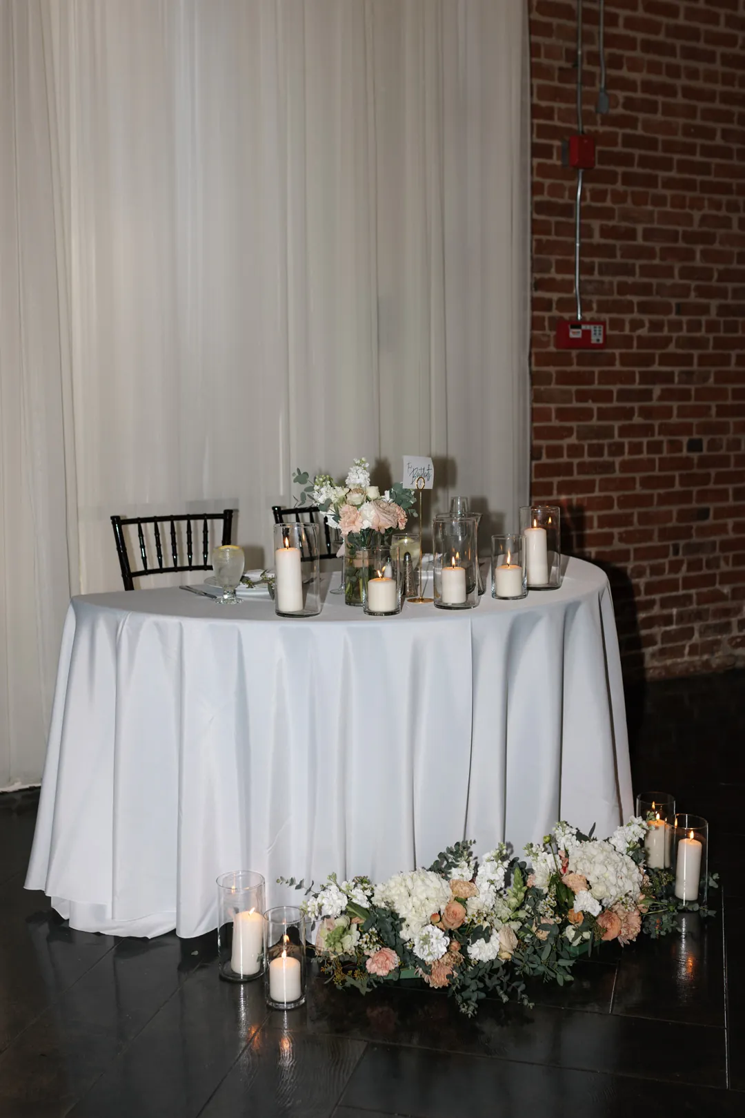 White-draped sweetheart table with flowers and chairs