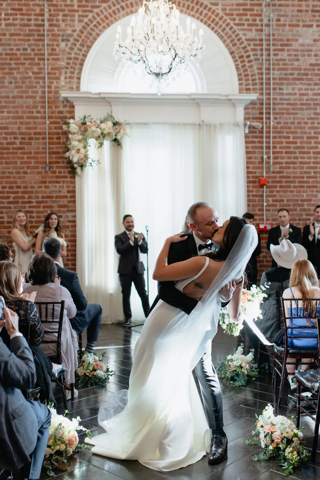 Newlyweds kissing in the ceremony aisle before guests