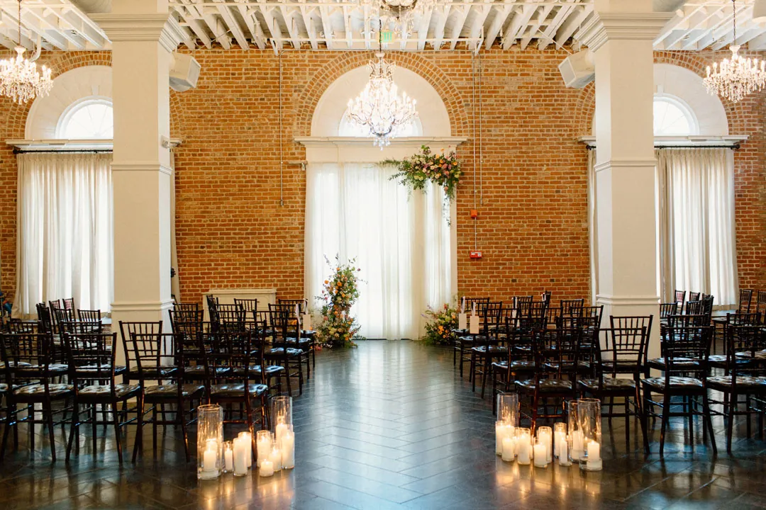 Rows of black ceremony chairs beneath chandeliers