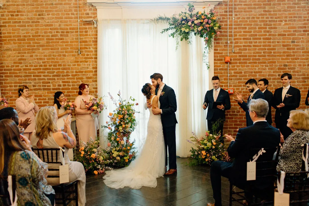 Couple exchanging vows before a floral ceremony backdrop