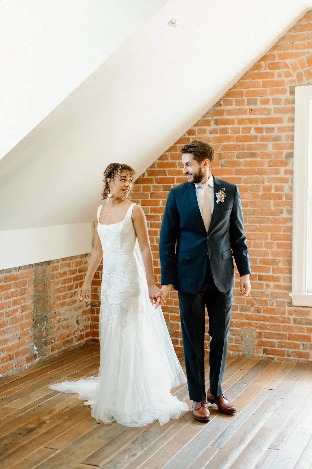 Couple standing together beside a sunlit window