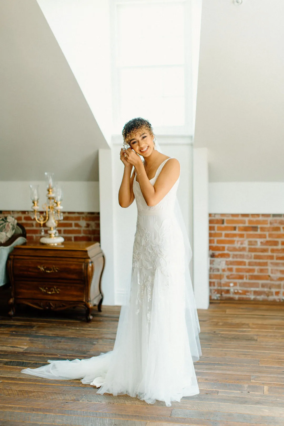Bride covering her face with her hands beneath a sloped ceiling