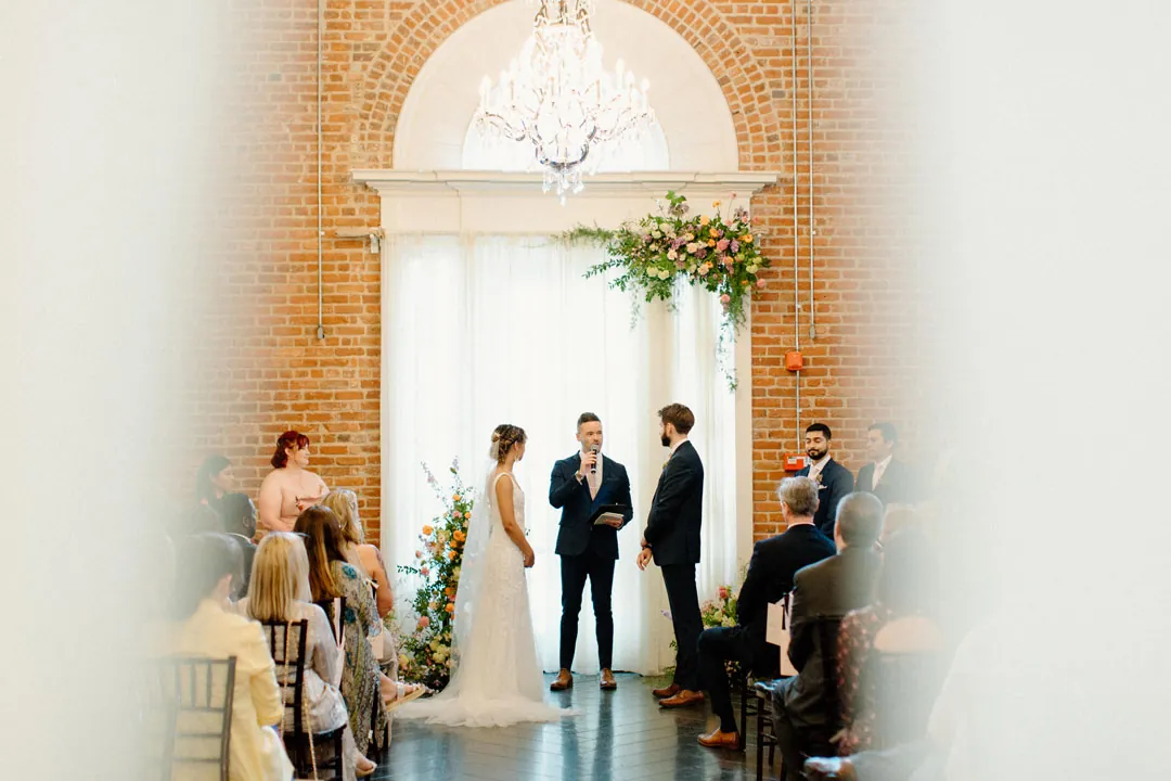 Wedding party assembled before a pale ceremony backdrop