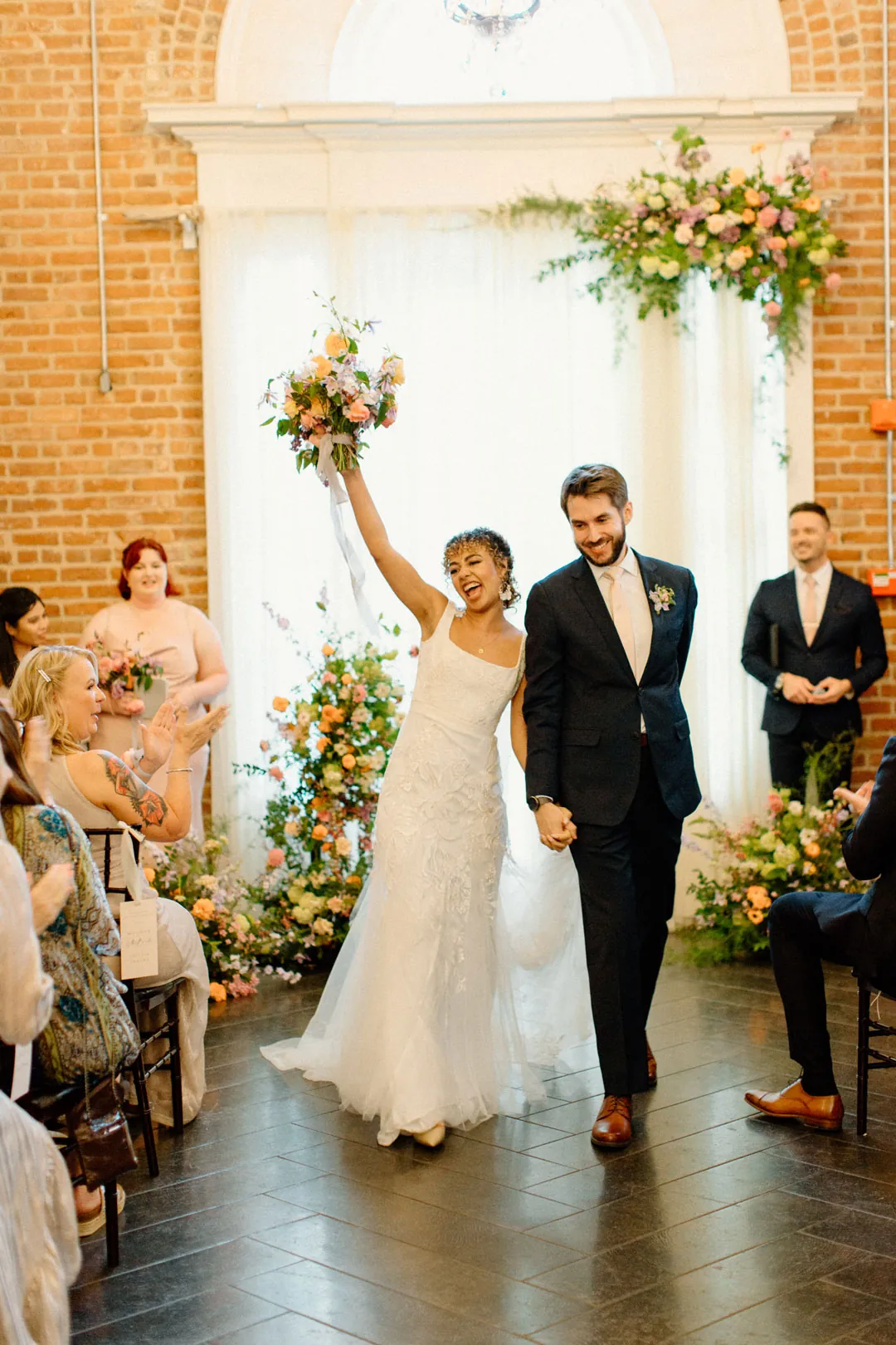 Newlyweds leaving the ceremony with their joined hands raised