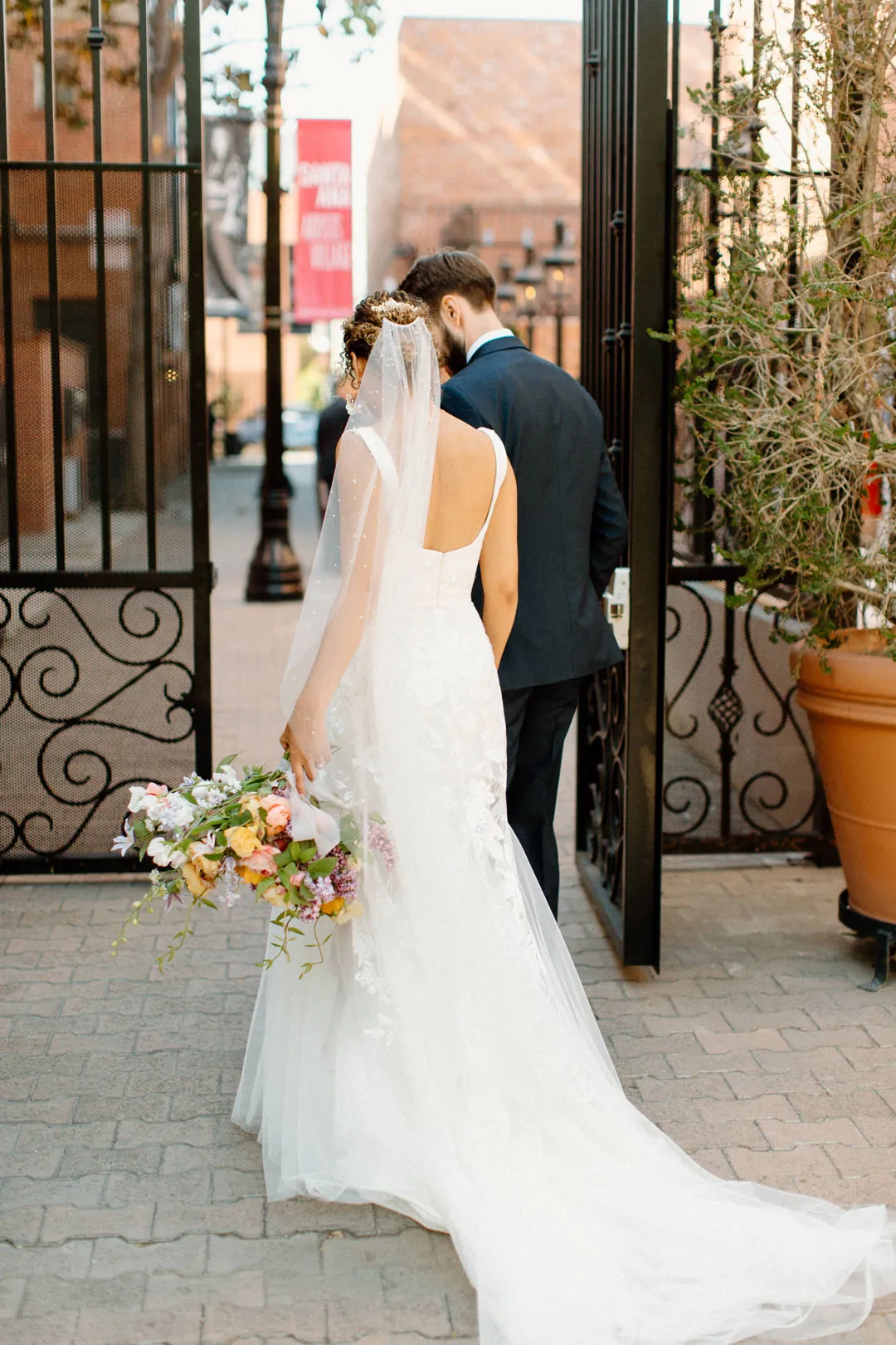 Couple embracing beside an open iron gate