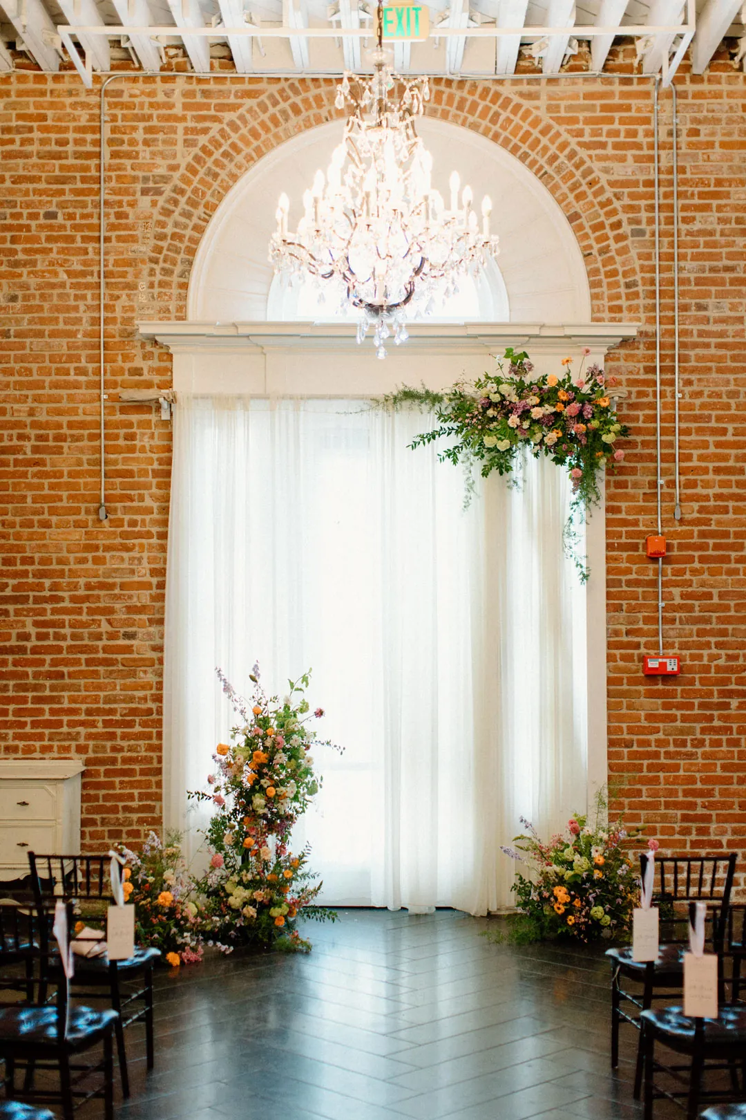 Floral ceremony arrangements beneath an arched window