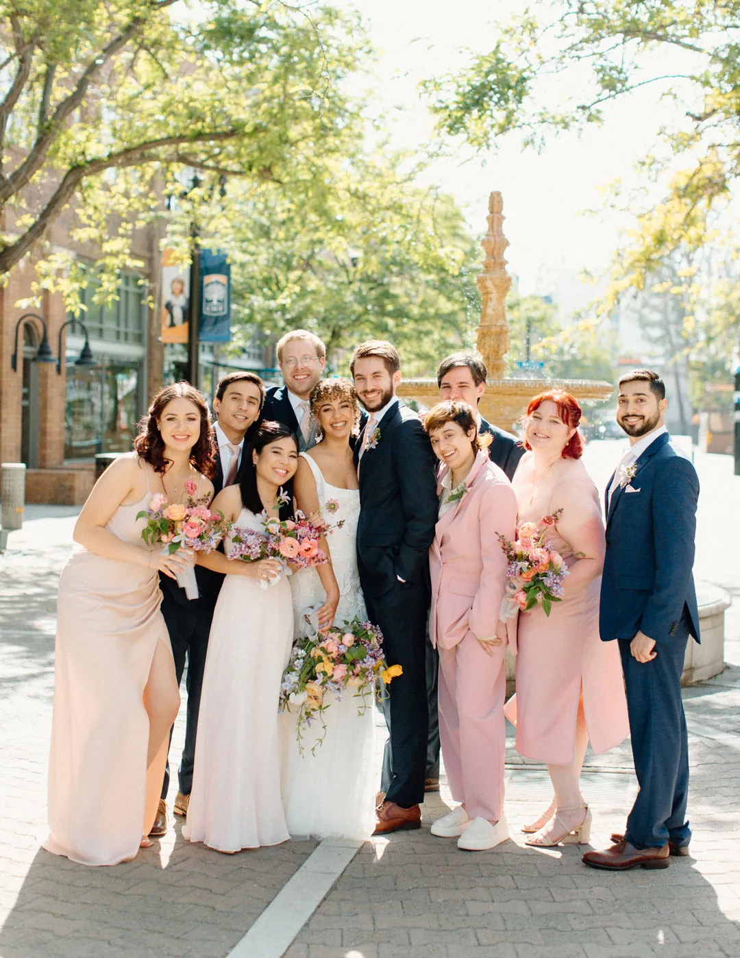 Wedding party posing on a tree-lined city street