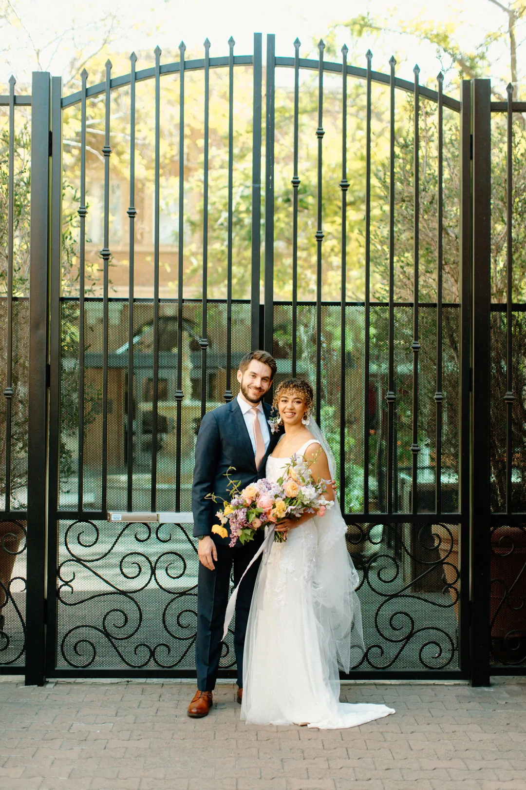 Couple seated together before a tall iron gate