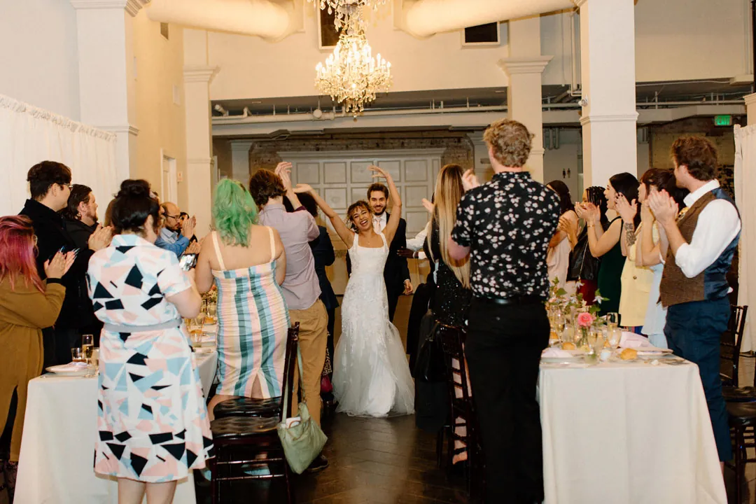 Guests celebrating as the couple enter their reception