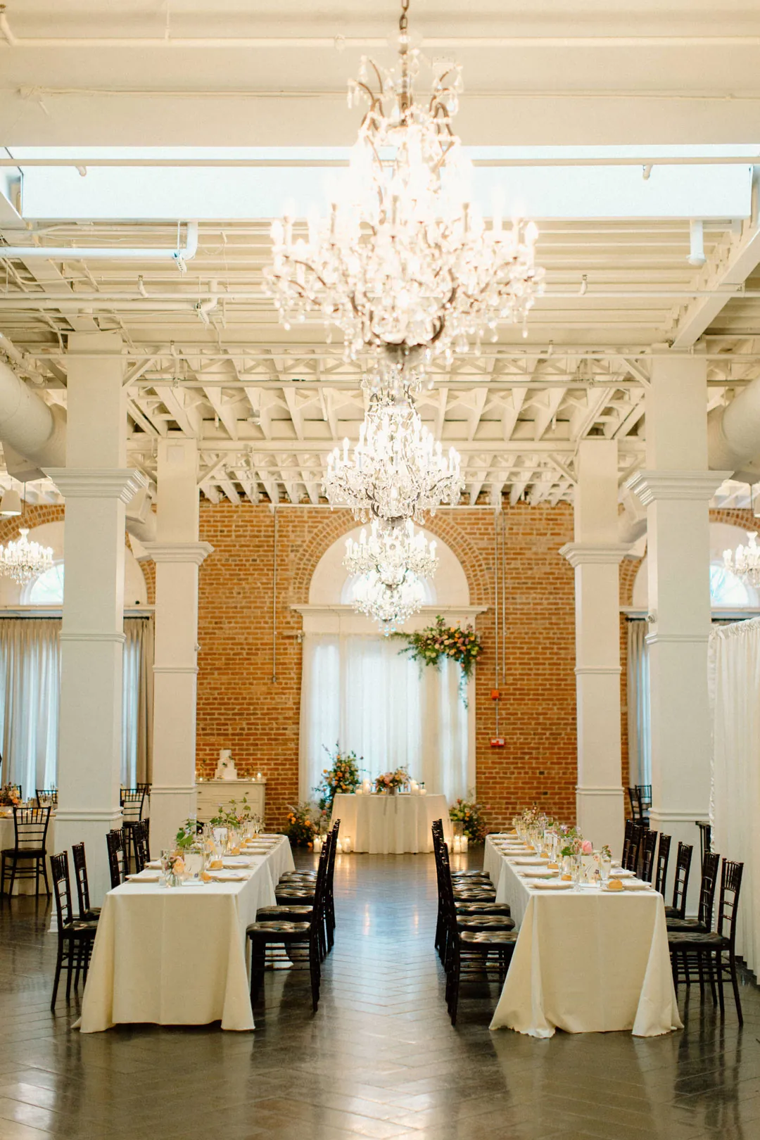 Reception tables arranged beneath a row of chandeliers