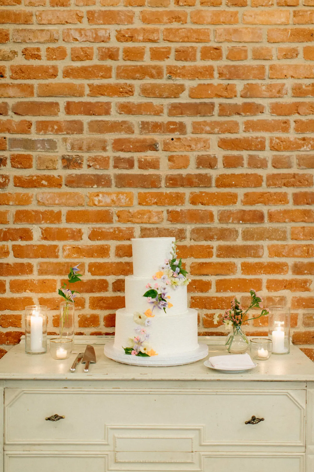 White wedding cake and candles on a dresser