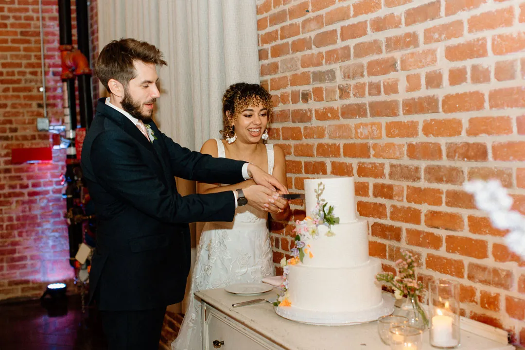 Couple cutting a white wedding cake together