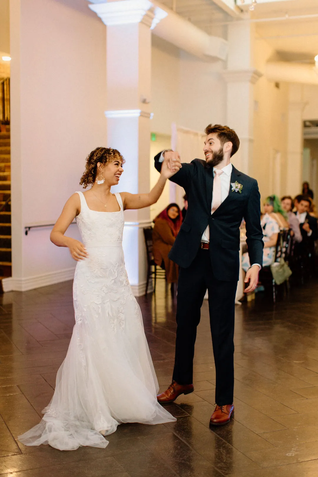 Couple raising glasses as they enter the reception room