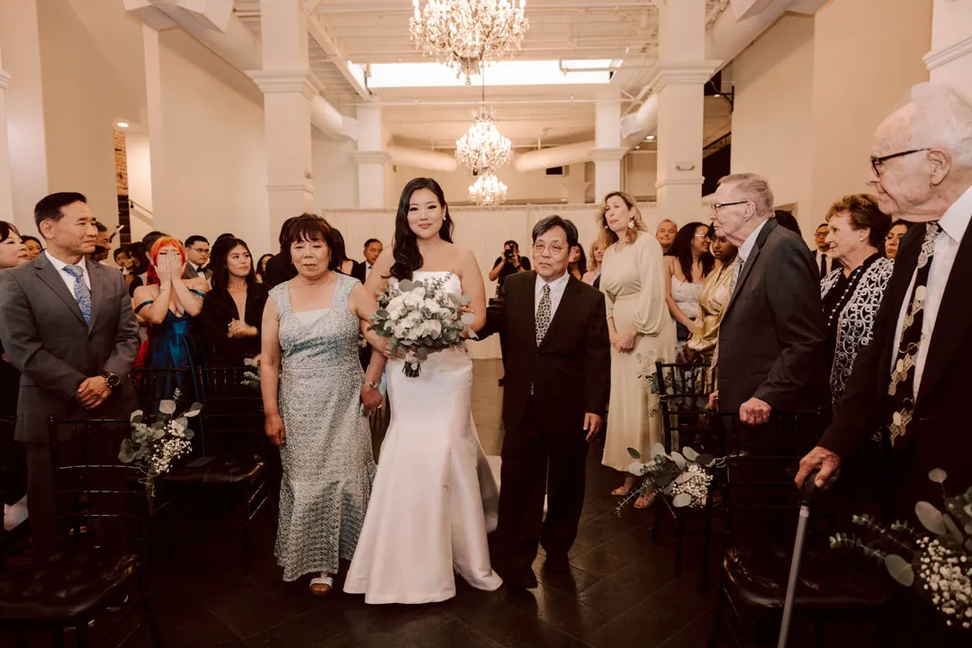 Bride walks between seated ceremony guests.