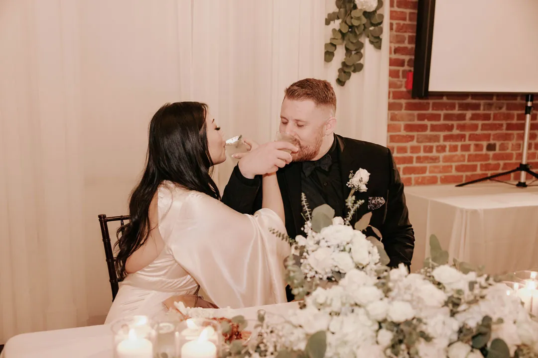 Newlyweds laugh together at their floral sweetheart table.