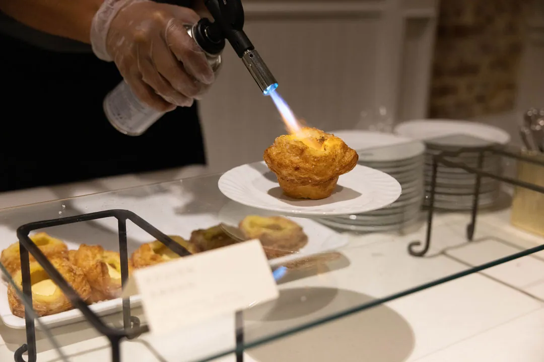Chef browns a pastry with a kitchen torch.