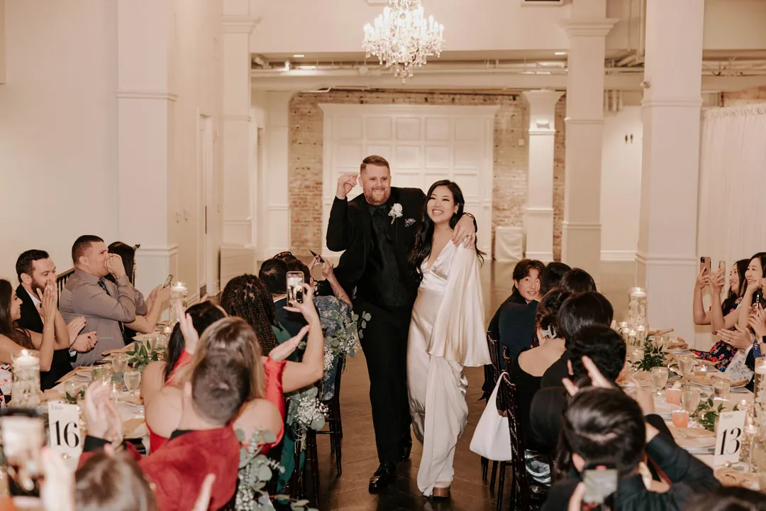 Couple enter the reception as guests turn toward them.